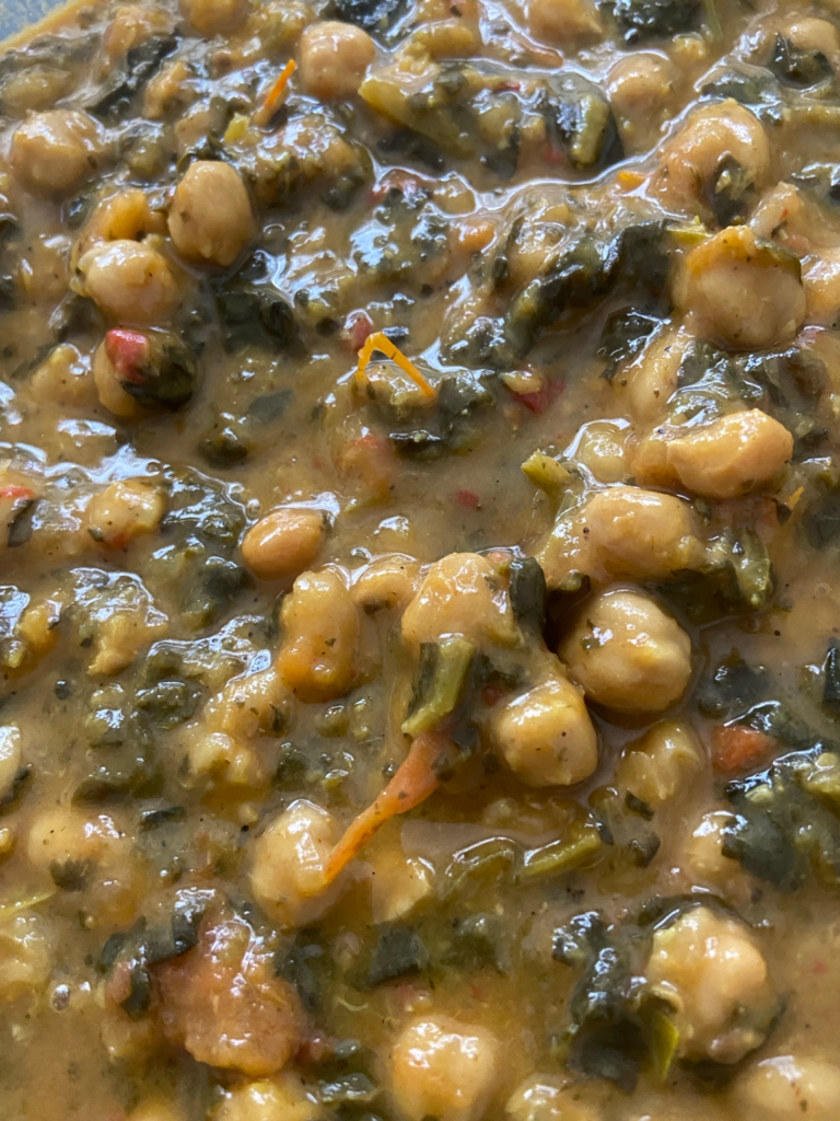 Close-up of creamy harissa tomato coconut chickpea stew with collard greens